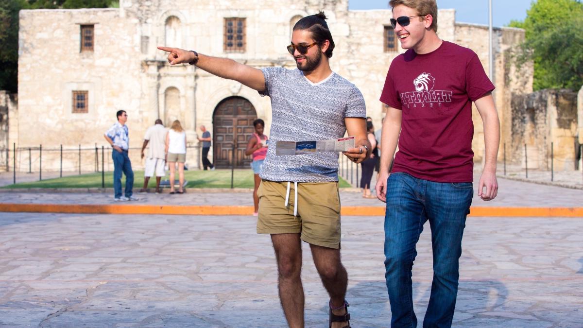 two students walk by The Alamo